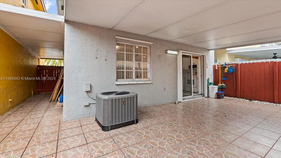 Covered outdoor area with an air conditioning unit and tiled floor.