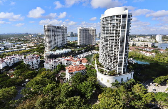 Aerial view of high-rise buildings and surrounding residential areas with water bodies and greenery.