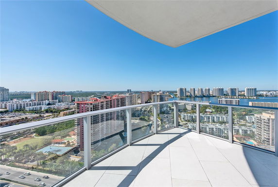 Panoramic view from a high-rise building balcony overlooking the cityscape and waterfront.