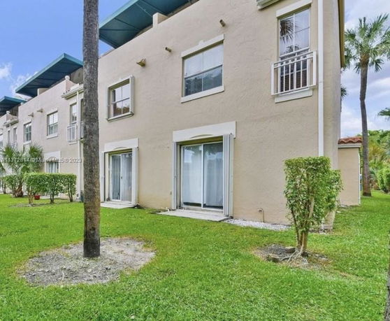 Side view of a multi-story residential building with beige exterior and sliding patio doors.