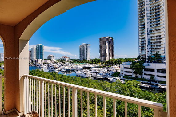 Panoramic view of a marina with yachts and tall buildings in the background.