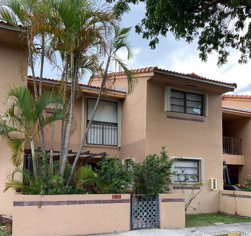 Front view of a two-story house with beige stucco walls and a tiled roof.