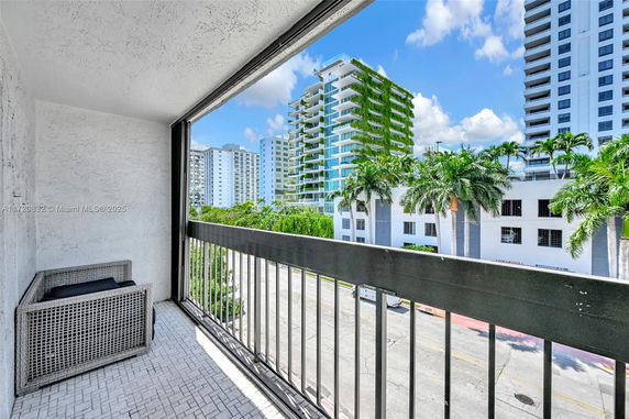 View from a balcony overlooking a street with modern residential buildings.