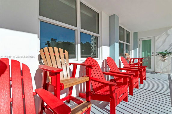 Outdoor seating area with red chairs on a house balcony.