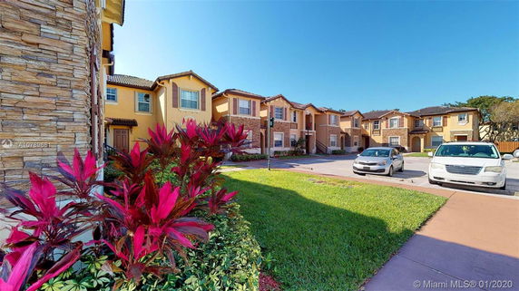 Front view of multi-story townhouses with brick and stucco exteriors.