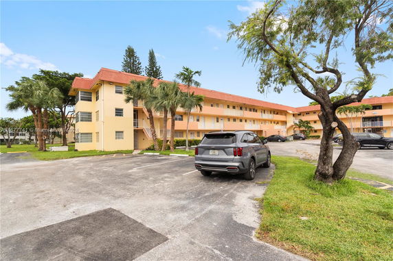 Front view of a multi-story residential building with parking area.