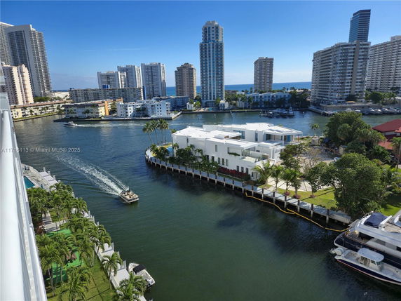 Panoramic view of high-rise buildings by a waterway with yachts and boats.