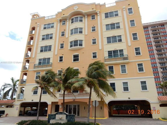 Front view of a multi-story residential building with a light orange facade and multiple balconies.