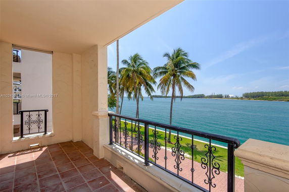 View from a balcony overlooking a body of water and palm trees.