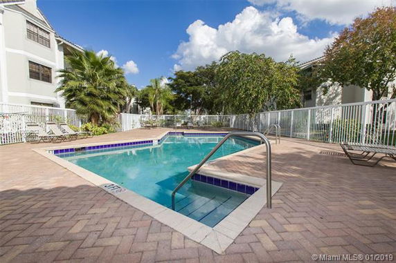 Small outdoor swimming pool with surrounding brick pavement and metal railing.