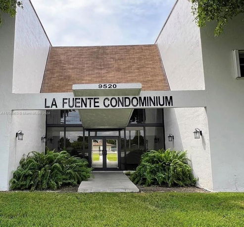 Front view of La Fuente Condominium entrance with glass doors and overhang.
