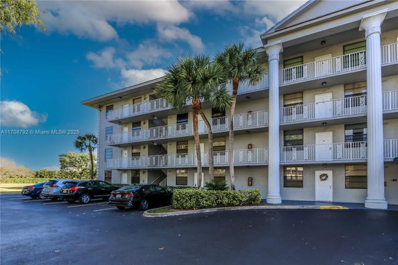 Front view of a multi-story residential building with balconies and large columns.