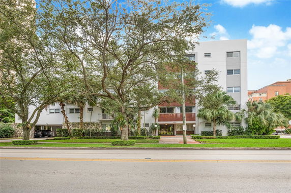 Front view of a multi-story building with trees in the foreground.
