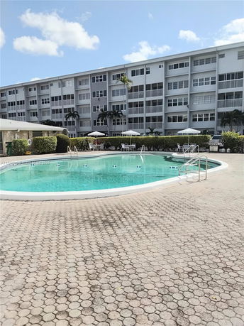 Outdoor swimming pool in front of a multi-story residential building.