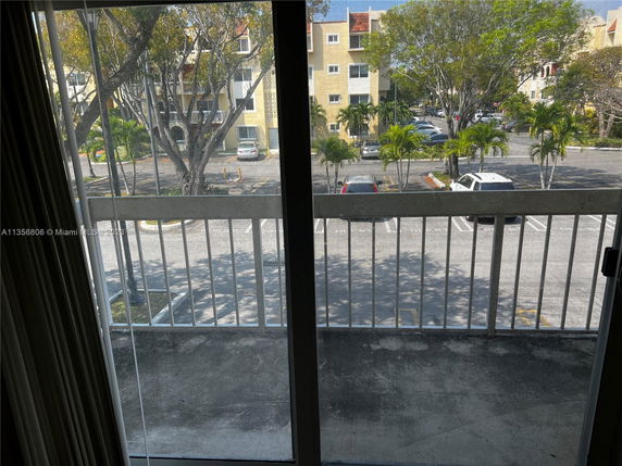 View from a balcony overlooking a parking area and residential buildings.