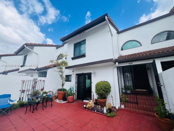 Front view of a two-story house with a tiled roof and patio area.