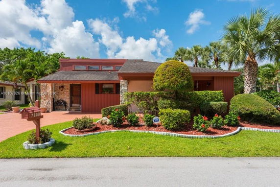 Front view of a house with a red brick exterior and landscaped garden.