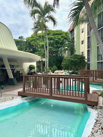 Pool area with a wooden bridge and surrounding greenery.