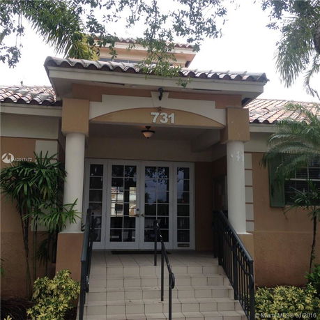 Front view of a building entrance with tiled roof and double doors.