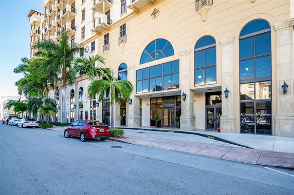 Front view of a multi-story building with large arched windows and palm trees in front.