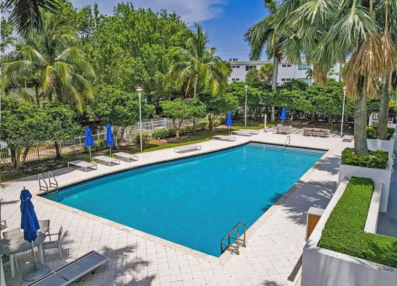 Outdoor swimming pool with surrounding lounge chairs and umbrellas.