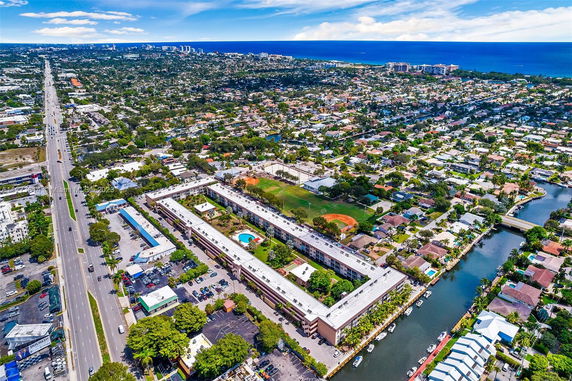 Aerial view of a coastal neighborhood with buildings, roads, and water channels.