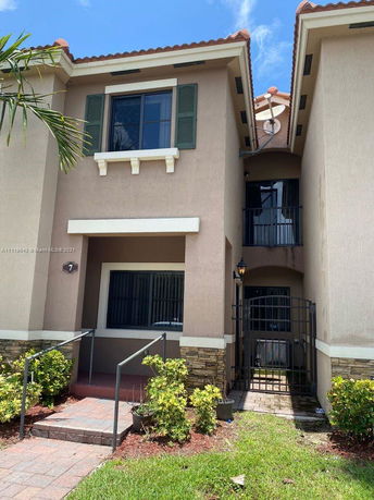 Front view of a two-story house with a balcony and gated entrance.