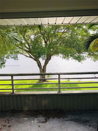 View from a building overlooking a tree and a body of water.