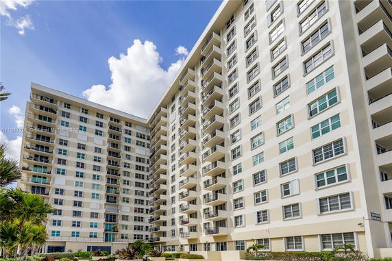 Front view of a multi-story residential building with balconies and large windows.