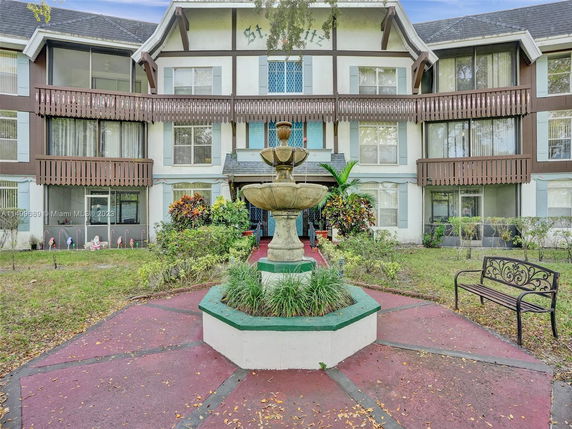 Front view of a multi-story residential building with a central fountain.