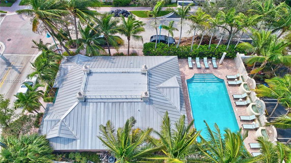 Aerial view of a building with a metal rooftop and adjacent swimming pool.