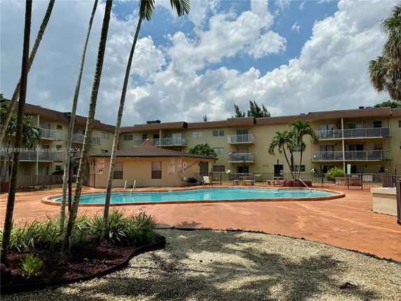 View of a residential complex with a communal swimming pool and surrounding buildings.