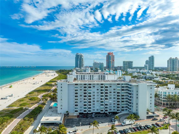 Aerial view of a beachfront area with several high-rise buildings and a sandy beach along a coastline.
