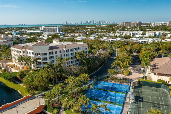 Aerial view of a residential complex with multi-story buildings, surrounded by trees and sports courts.