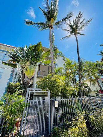Front view of a multi-story house surrounded by palm trees.