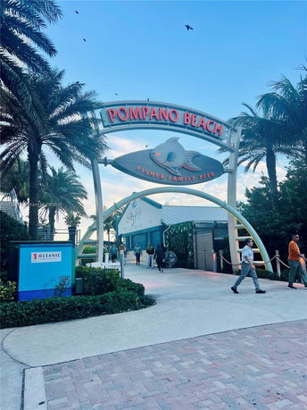 Entrance of a pier with a sign reading 'Pompano Beach Fisher Family Pier'.