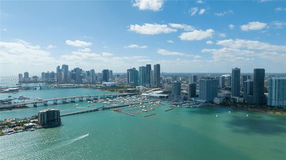 Panoramic view of a city skyline with tall buildings, bridges, and a marina on the waterfront.