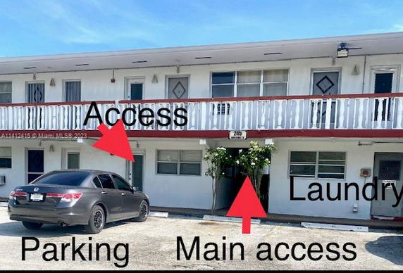 Front view of a two-story building with a balcony and parking area.