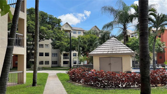 View of multi-story residential buildings with trees and a small structure in the foreground.
