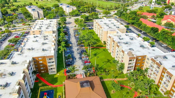 Aerial view of a residential complex with multiple apartment buildings, parking areas, and green spaces.