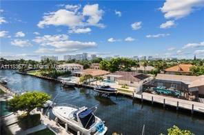 Panoramic view of a residential area with a canal and boats, surrounded by houses.