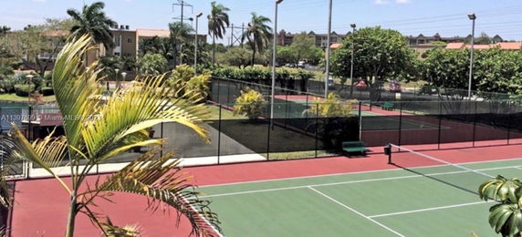 View of tennis courts surrounded by greenery.