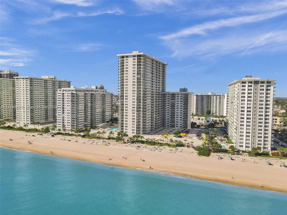 Aerial view of a beachfront high-rise apartment complex with multiple buildings facing the ocean.