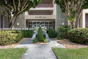 Front view of building with entrance and surrounding greenery.