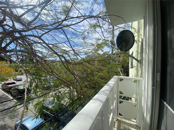 View from a building balcony with a satellite dish and surrounding trees.