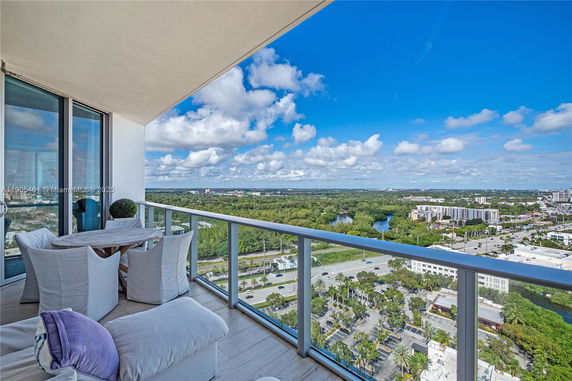 Balcony overlooking a cityscape with greenery and urban buildings.