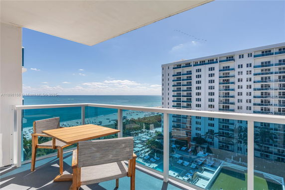 Panoramic view from a balcony overlooking the ocean and a high-rise building.