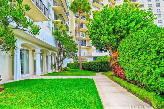 View of a multi-story residential building with balconies surrounded by green landscaping.