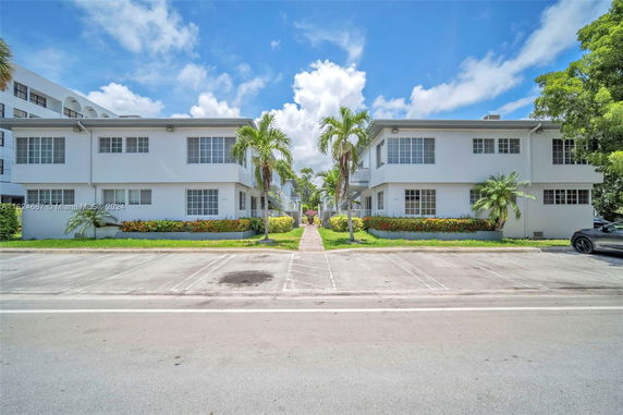 Front view of two-story residential buildings with a walkway and landscaped area in between.