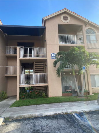 Front view of a two-story residential building with balconies and exterior stairs.